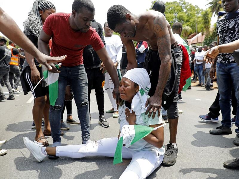 A Nigerian woman based in South Africa weep as others comfort her during a protest outside their embassy in Pretoria on October 21, 2020 in solidarity with Nigerian youth who are demanding an end to police brutality in the form of The Nigerian Police Force Unit, Special Anti-Robbery Squad (SARS). Phill Magakoe / AFP