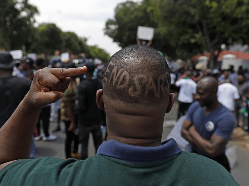 A Nigerian based in South Africa shows the middle finger and words "EndSars" shaved on his head during a protest outside the Nigerian embassy in Pretoria on October 21, 2020 in solidarity with Nigerian youth who are demanding an end to police brutality in the form of The Nigerian Police Force Unit, Special Anti-Robbery Squad (SARS). Phill Magakoe / AFP