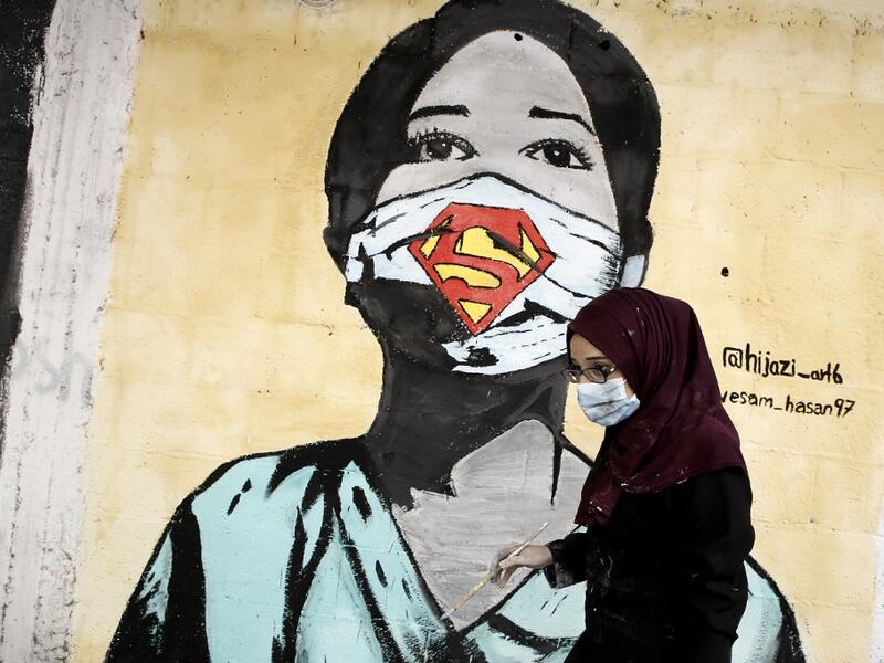 A Palestinian artist paints a mural of a mask-clad schoolgirl in Gaza City on October 22, 2020, amid the novel coronavirus pandemic crises. Mohammed ABED / AFP