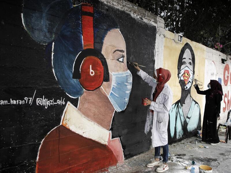 Palestinian students paint murals of mask-clad young girls in Gaza City on October 22, 2020, amid the novel coronavirus pandemic crises. Mohammed ABED / AFP