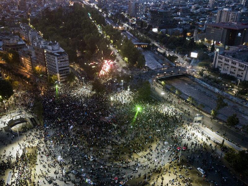Aerial view of Plaza Italia square showing people gathering as they wait for the official result on the constitutional referendum voting, in Santiago on October 25, 2020. A year to the day after more than one million people thronged downtown Santiago in the biggest Chile's social uprising, Chileans vote Sunday on whether to change the country's dictatorship-era constitution seen as underpinning the nation's glaring inequalities. JAVIER TORRES / AFP