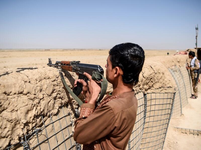 In this photo taken on September 27, 2020, a policeman keeps watch at an outpost set up against Taliban fighters at Aziz Abad village in Maiwand district of Kandahar province. The dry and dusty village of Aziz Abad in Maiwand district sits on the frontline of Afghanistan's war and is currently under government control -- but only just. WAKIL KOHSAR / AFP