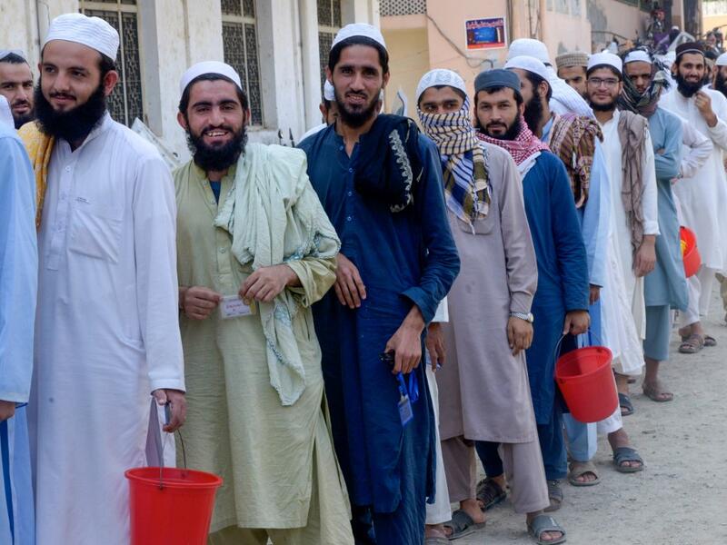 In this picture taken on October 19, 2020 Islamic seminary students wait to collect food at the Darul Uloom Haqqania seminary in Akora Khattak. The Darul Uloom Haqqania seminary has churned out a who's who of Taliban top brass -- including many now on the hardline group's negotiating team holding talks with the Kabul government to end a 20-year war. Abdul MAJEED / AFP