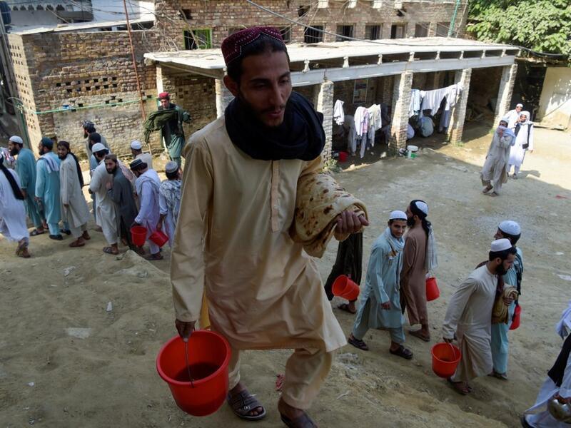In this picture taken on October 19, 2020 Islamic seminary students wait to collect food at the Darul Uloom Haqqania seminary in Akora Khattak. The Darul Uloom Haqqania seminary has churned out a who's who of Taliban top brass -- including many now on the hardline group's negotiating team holding talks with the Kabul government to end a 20-year war. Abdul MAJEED / AFP