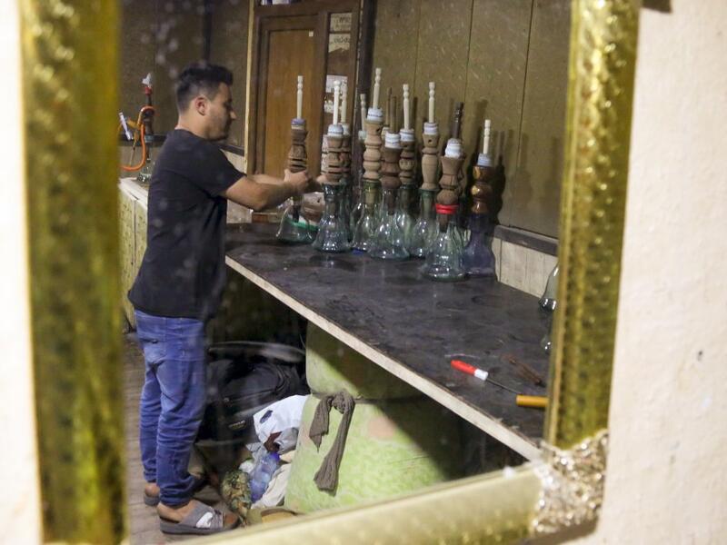 An employee cleans narguilehs (water pipes) at a coffee shop in Iraq's central holy city of Karbala on October 21, 2020. The business of strictly gender-separated cafes has carried on, despite the heavy health risks associated with smoking and a full-blown pandemic that has brought an average of 4,000 new coronavirus cases a day to Iraq. Mohammed SAWAF / AFP