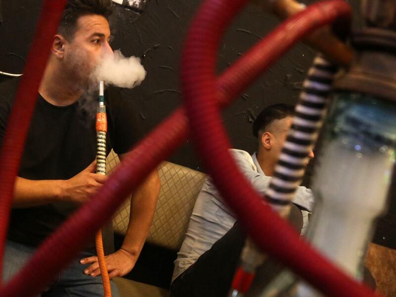 Iraqi men smoke narguileh (water pipe) at a coffee shop in Iraq's central holy city of Karbala on October 21, 2020. The narguileh business of strictly gender-separated cafes has carried on, despite the heavy health risks associated with smoking and a full-blown pandemic that has brought an average of 4,000 new coronavirus cases a day to Iraq. Mohammed SAWAF / AFP
