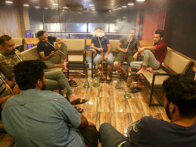Iraqi men smoke narguileh (water pipe)at a coffee shop in Iraq's central holy city of Karbala on October 21, 2020. The business of strictly gender-separated cafes has carried on, despite the heavy health risks associated with smoking and a full-blown pandemic that has brought an average of 4,000 new coronavirus cases a day to Iraq. Mohammed SAWAF / AFP