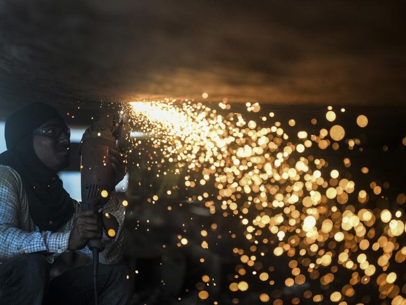 In this picture taken on November 11, 2020 a dockyard worker carries on maintenance works on the hull of a ship on the banks of the Buriganga River in Char Kaliganj on the outskirts of Dhaka. Rivers are the lifeblood of the delta nation of 168 million people where much of the low-lying land is accessed via boat, with Bangladesh's strong economic growth of recent years fuelling more investments in new and bigger ships. Munir UZ ZAMAN / AFP