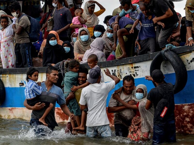 This photo taken on June 25, 2020 shows six-year-old daughter Nosmin Fatima (bottom L) being carried off a boat as she and her mother Majuma land with other Rohingya migrants in Lhokseumawe in North Aceh Regency. Weeks after a funeral for the wife and daughter he thought had died at sea while trying to sail to him, Nemah Shah was stunned when he saw online images of them emerging from a refugee boat in Indonesia. MUNIR UZ ZAMAN / AFP