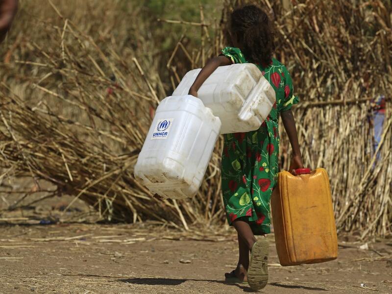 An Ethiopian refugee girl walks carrying water containers at Um Raquba camp in Sudan's eastern Gedaref province on November 28, 2020. Sudan needs $150 million in aid to cope with the flood of Ethiopian refugees crossing its border from conflict-stricken Tigray, the UN refugee agency chief said during a visit to a camp. ASHRAF SHAZLY / AFP