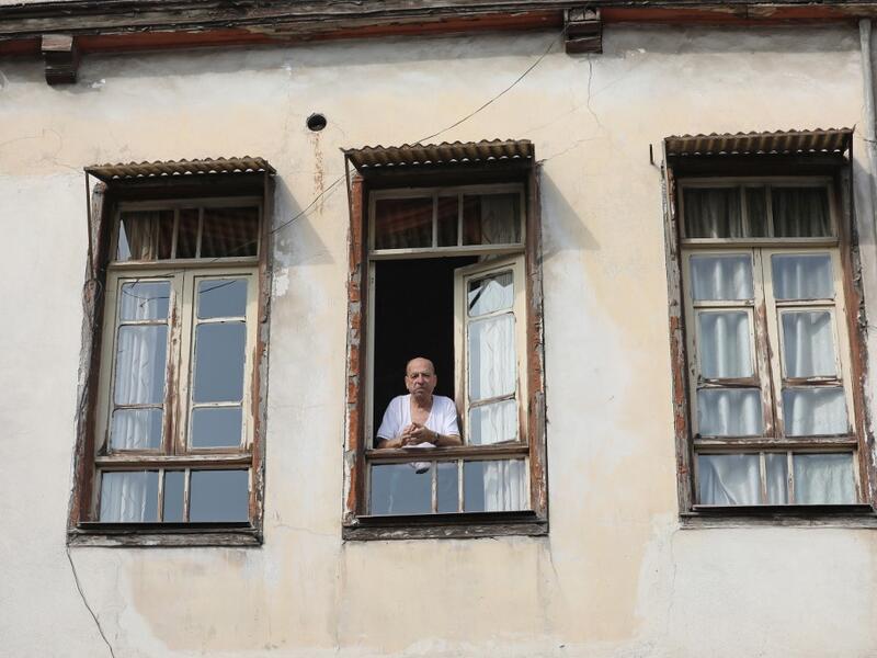 A man looks out the window in the old part of Syria's capital Damascus on October 28, 2020. The old city of the Syrian capital is famed for its elegant century-old houses, usually two storeys built around a leafy rectangular courtyard with a carved stone fountain at its centre. While the capital has been largely spared the violence of Syria's almost ten-year war, several of these traditional homes have been abandoned by their owners or damaged in the conflict. LOUAI BESHARA / AFP