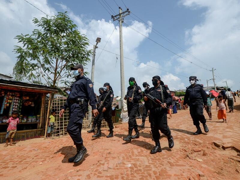 In this photograph taken on October 7, 2020, Rapid Action Battalion (RAB) personnel patrol along a street in Jamtoli refugee camp for Rohingyas in Ukhia. Boatloads of Rohingya landing across Southeast Asia are victims of complex human trafficking networks run by a dizzying web of players, from crime bosses and corrupt cops to poor fishermen, rickshaw drivers and even Rohingya themselves. Munir UZ ZAMAN / AFP