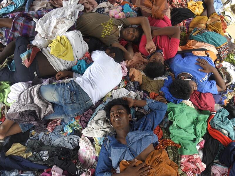 This file picture taken on September 8, 2020 shows a group of Rohingya men sleeping on a pile of donated clothes at a transit camp after nearly 300 Rohingya migrants came ashore on the beach in Lhokseumawe on the northern coast of Indonesia's Sumatra island. Boatloads of Rohingya landing across Southeast Asia are victims of complex human trafficking networks run by a dizzying web of players, from crime bosses and corrupt cops to poor fishermen, rickshaw drivers and even Rohingya themselves. Rahmat Mirza / A
