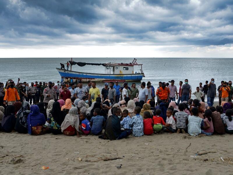 In this file photo taken on June 25, 2020 Rohingya migrants sit by the beach after their boat landed on the shores of Lancok village, in Indonesia's North Aceh Regency. Boatloads of Rohingya landing across Southeast Asia are victims of complex human trafficking networks run by a dizzying web of players, from crime bosses and corrupt cops to poor fishermen, rickshaw drivers and even Rohingya themselves. CHAIDEER MAHYUDDIN / AFP