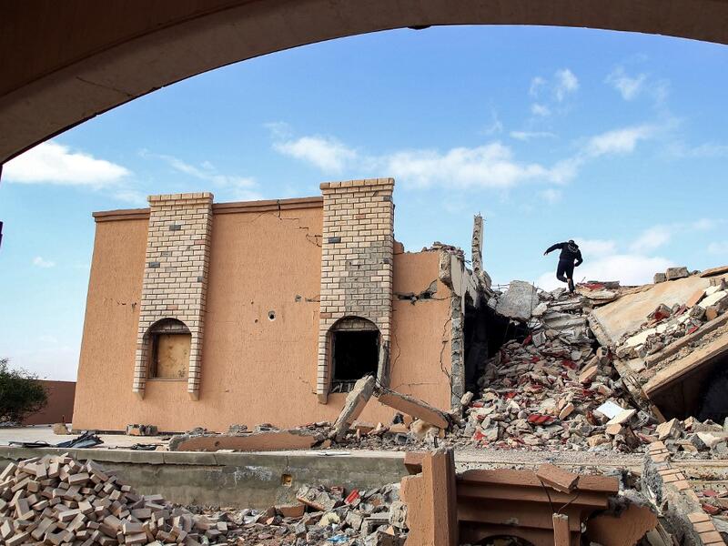 A youth climbs the rubble of a destroyed building in the city of Tawergha, some 200 kilometres (125 miles) east of Libya's capital close to the port city of Misrata, on December 12, 2020. When Libyan dictator Moamer Kadhafi was toppled, people took revenge on those they saw as his supporters -- including the entire town of Tawergha, whose 40,000 residents were forced to flee. Now, almost a decade later since militia forces rampaged through the town torching homes, destroying buildings and leaving farms in r