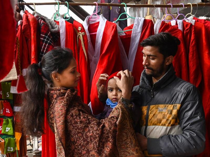 In this picture taken on December 15, 2020, a Christian family buys a Santa Claus outfit for their son at a shop ahead of Christmas celebrations in Lahore. Arif ALI / AFP