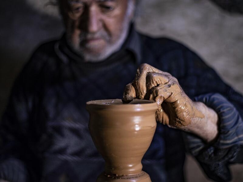 Syrian-Armenian potter Misak Antranik Petros uses an ancient pottery wheel to churn different types of pots at his workshop located inside an ancient mud-brick house near the city of Qamishli in Syria's northeastern Hasakeh province, on December 19, 2020. Petros was only a teenager when he had to take over for his sick father and become the main potter of the family. He has since become a master of the craft, and is keen to pass his skills on.  Delil SOULEIMAN / AFP