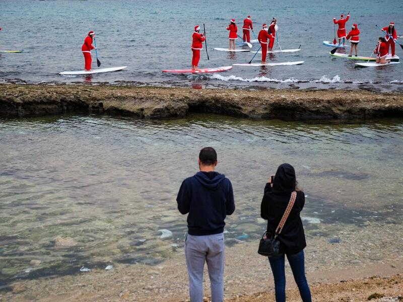 Lebanese people dressed in Santa Claus outfits ride on standup paddles in Lebanon's northern coastal city of Batroun on December 22, 2020. Ibrahim CHALHOUB / AFP