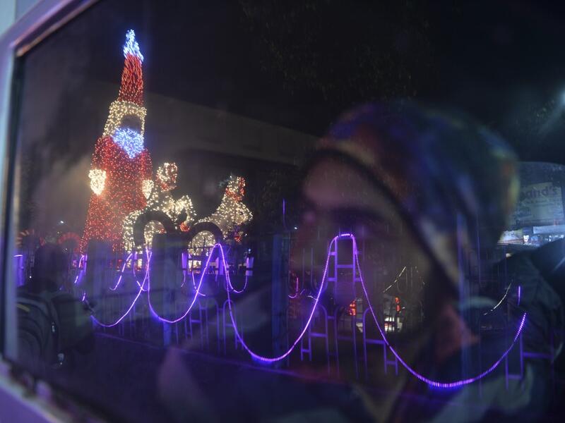 A car driver looks at a model of Santa Claus illuminated, on the eve of Christmas in Siliguri on December 24, 2020. DIPTENDU DUTTA / AFP