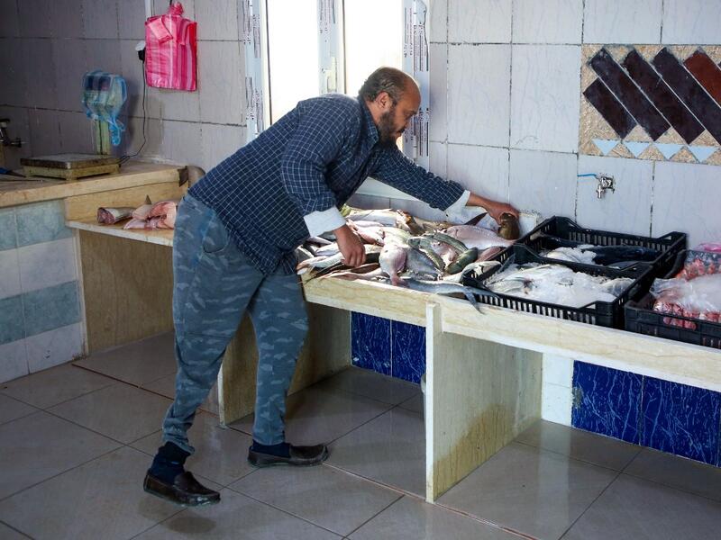 Libyan fishmonger Radwan Jibril who uses a prosthetic leg after an injury amid clashes in 2011, works at his shop in the port city of Misrata, on December 17, 2020. With Libya's health sector left in tatters by its multiple conflicts since the 2011 revolution, war-wounded Libyans are often sent abroad for treatment, at the expense of the state. However, A national centre for prostheses, being established in Misrata, already has a patient waiting list of more than 3,000 amputees