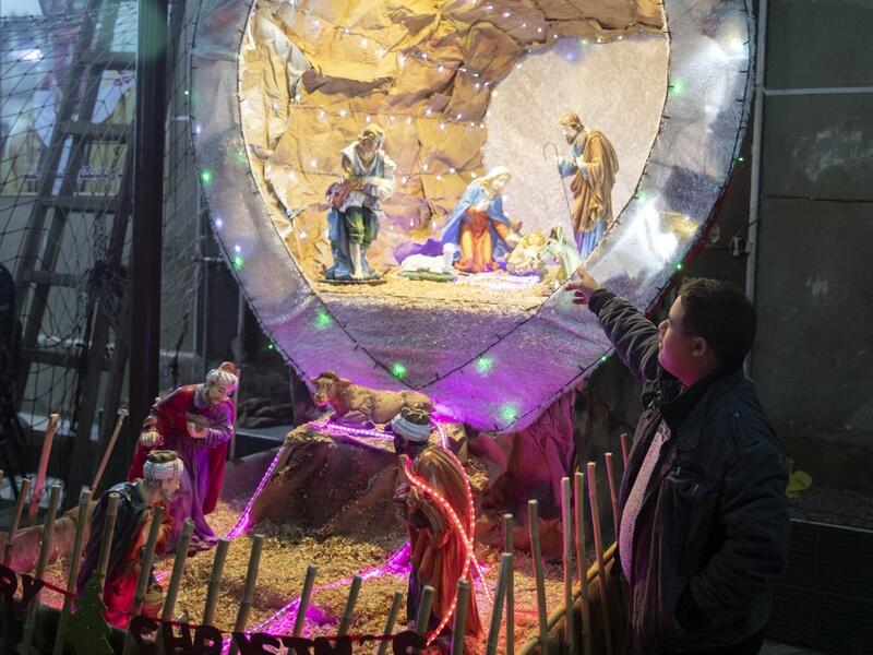 An Egyptian Christians worshipper stands by a nativity scene as he attends the Christmas Eve mass at the Coptic Catholic St. Mark Church in Minya city, some 245 kilometres south of the capital Cairo on January 6, 2021.   Roger ANIS / AFP