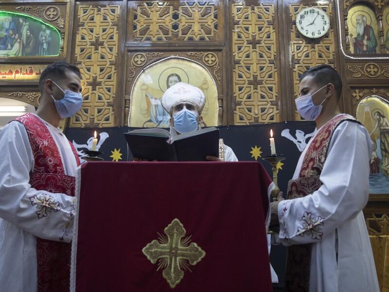 An Egyptian Coptic priest (C) holds Christmas Eve mass at the Coptic Catholic St. Mark Church in Minya city, some 245 kilometres south of the capital Cairo on January 6, 2021.   Roger ANIS / AFP