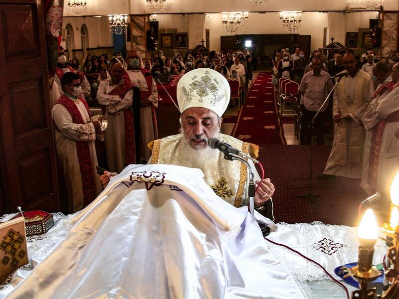 A Sudanese Coptic priest heads the Christmas midnight mass at the capital Khartoum's Martyrs Church late on January 6, 2021, as the Orthodox Christian faith uses the old Julian calendar in which Christmas falls 13 days after the date in the more widespread Gregorian calendar.  Ebrahim HAMID / AFP