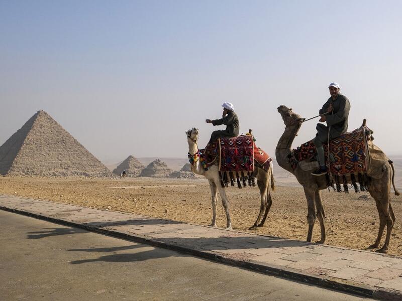Camel trainers ride camels awaiting tourists by the Pyramid of Menkaure (Menkheres) at the Giza Pyramids Necropolis on the western outskirts of the Egyptian capital's twin city of Giza on January 7, 2021. Amir MAKAR / AFP