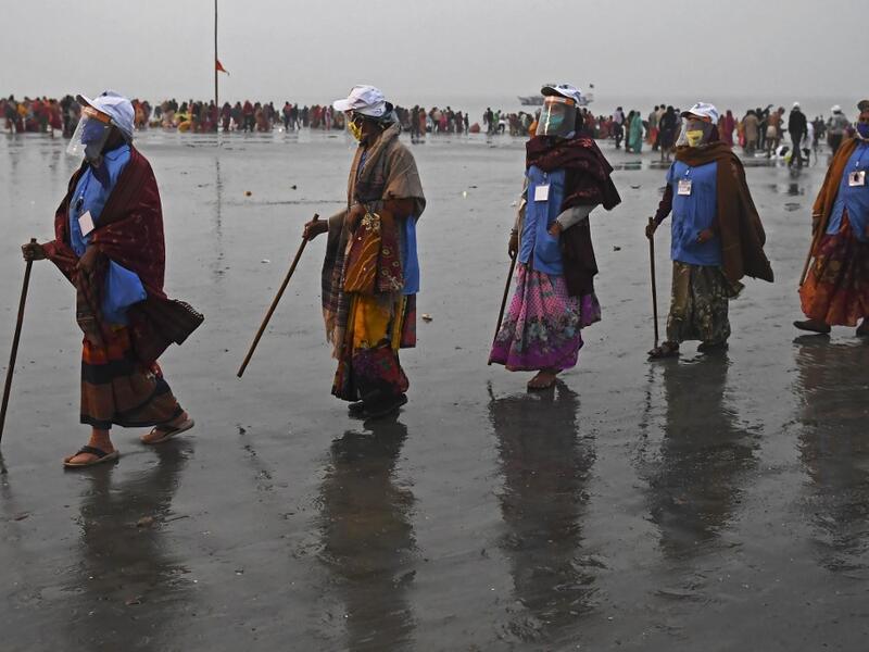 Members of local village panchayat wearing face shields and masks inspect the sanitization on the beach as a preventive measure against the Covid-19 coronavirus at the confluence of Ganges and the Bay of Bengal during the Gangasagar Mela on the occasion of Makar Sankranti, a day considered to be of great religious significance in Hindu mythology, at Sagar Island, around 150 kms south of Kolkata on January 14, 2021. Dibyangshu SARKAR / AFP