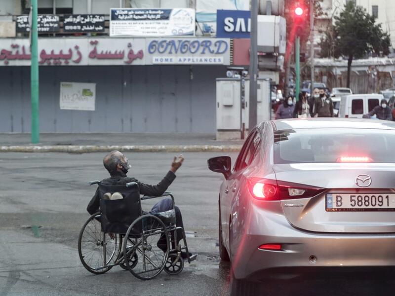 A wheelchair-bound beggar is seen next to a car stopping at a red light, in Lebanon's capital Beirut on January 16, 2021, despite a total lockdown due to the COVID-19 coronavirus pandemic. ANWAR AMRO / AFP