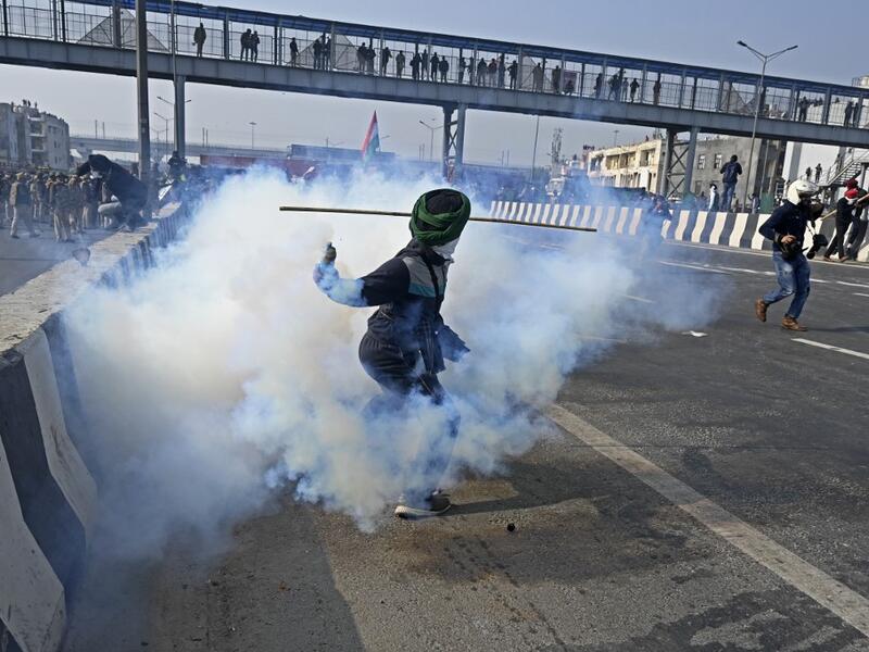 A farmer throws back a tear gas shell towards police during a tractor rally as farmers continue to protest against the central government's recent agricultural reforms in New Delhi on January 26, 2021. Sajjad HUSSAIN / AFP