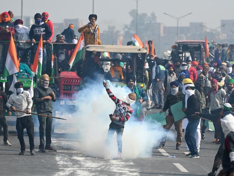 A farmer throws back a tear gas shell fired by the police to disperse them during a tractor rally as farmers continue to demonstrate against the central government's recent agricultural reforms in New Delhi on January 26, 2021. Sajjad HUSSAIN / AFP
