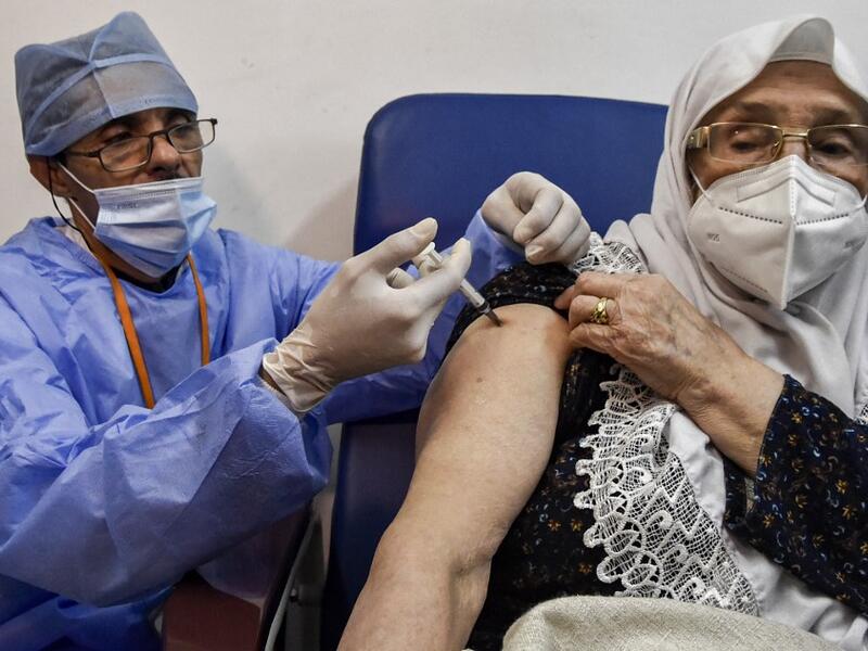 A medical worker administers a dose of Russia's Sputnik V vaccine for COVID-19 coronavirus disease upon a woman at a clinic in the city of Blida, about 45 kilometres southwest of the Algerian capital, on January 30, 2021, where the North African country is symbolically starting its vaccination drive at the same place to have registered the first novel coronavirus case in 2020. At the end of December, Algiers announced an order of 500,000 doses of Sputnik V vaccine from its Russian ally. RYAD KRAMDI / AFP