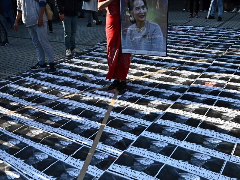 A Myanmar activist holds a portrait of Myanmar's de facto leader Aung San Suu Kyi as portraits of the country's military general Min Aung Hlaing are seen on the floor during a a protest outside the United Nations University building in Tokyo on February 1, 2021 following a military coup in the country by a general after arresting civilian leader Aung San Suu Kyi and other senior officials. Philip FONG / AFP