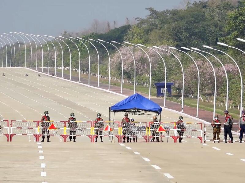 Soldiers stand guard on a blockaded road to Myanmar's parliament in Naypyidaw on February 1, 2021, after the military detained the country's de facto leader Aung San Suu Kyi and the country's president in a coup. STR / AFP