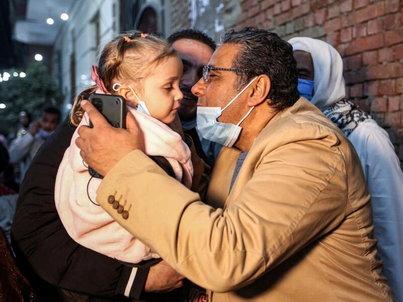 Mahmoud Hussein (R), an Egyptian national and senior journalist for Qatar-based Al Jazeera Arabic, kisses a child upon his arrival at his family home in the Giza village of Zawyet Abu Musallam, about 30 kilometres south of Egypt's capital Cairo on February 6, 2021 upon his release from detention. Egypt has freed the journalist for Qatar's Al Jazeera after four years in jail without trial following the end last month of a rift between the two Arab states. Mahmoud Hussein, an Egyptian national who had been im