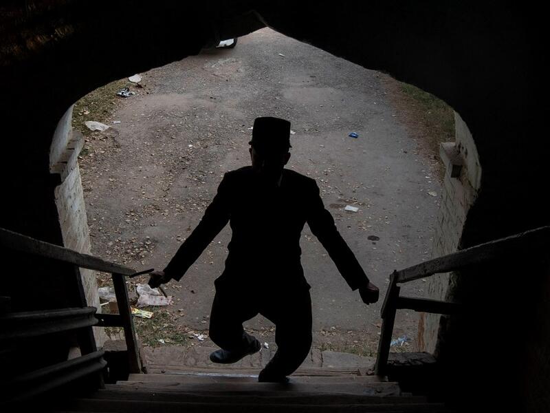 In this picture taken on February 9, 2021, street actor Usman Khan, dressed up as silent film star Charlie Chaplin, performs in the Pakistan's northwestern city of Peshawar. Wearing a bowler hat and familiar toothbrush moustache, Pakistan's Usman Khan darts through traffic swinging a cane, teasing motorists and shopkeepers for laughs and a few rupees with a Charlie Chaplin impersonation that has become a viral sensation.  Abdul MAJEED / AFP