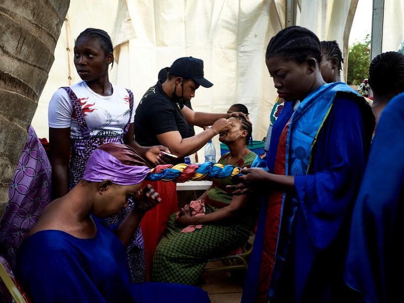 Gold miners are helped to get ready in the backstage prior to take part in a fashion show as part of the first edition of the International Gold Fair Afrik'Or, in Bamako, on February 12, 2021. The Princess of Burundi Esther Kamatari, selected 34 women among gold mines workers in southern Mali, to walk down the catwalk for a fashion show organised during the International Gold Fair. Gold represents 15% of Mali's exports and more than 20% of its GDP estimated at nearly US$20 billion by the end of 2019. MICHEL