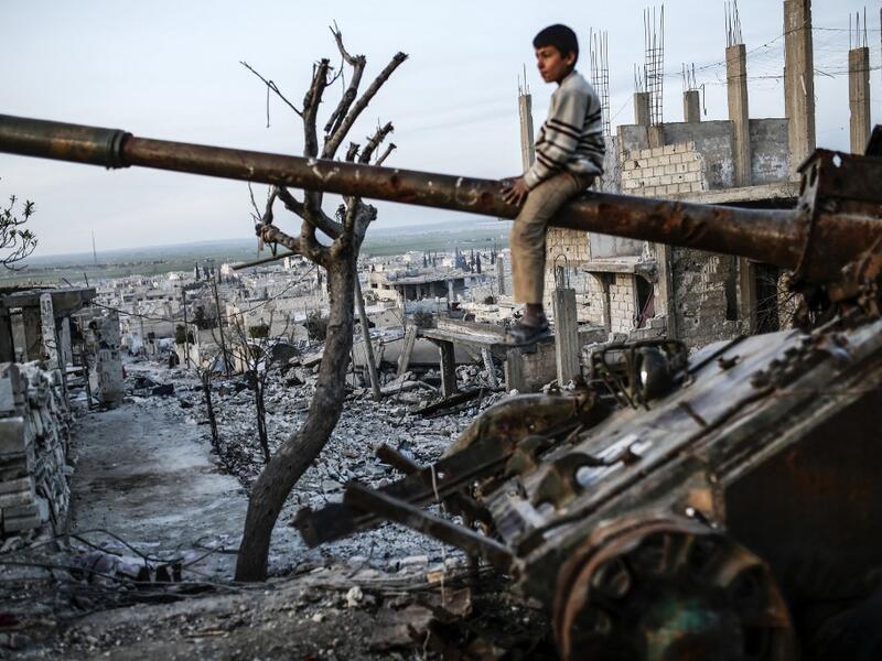  Syrian Kurdish boy sits on a destroyed tank in the Syrian town of Kobane