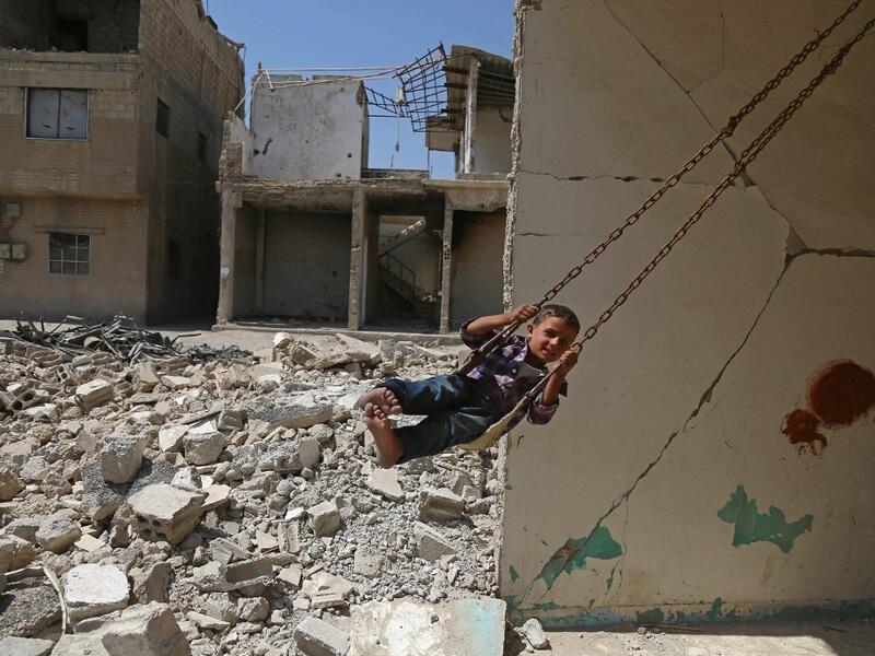  Syrian boy plays on a swing in a destroyed building