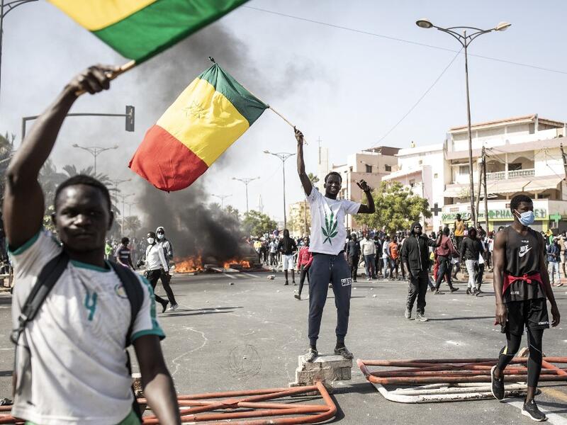 Protesters wave the Senegalese national flag during a protest in Dakar on March 8, 2021, after the country's opposition leader Ousmane Sonko was charged with rape. Usually considered a beacon of stability in a volatile region, deadly clashes between opposition supporters and security forces have rocked the West African state. JOHN WESSELS / AFP