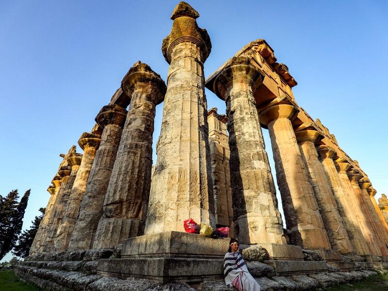 A costumed actress sits by a column during the filming of a television production at the Temple of Zeus in the ruins of Libya