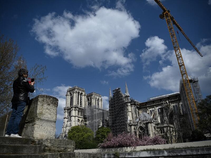 A woman takes pictures of Notre-Dame de Paris cathedral