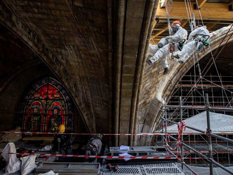 Rope access technicians plaster stonework on a damaged vault of the Notre-Dame de Paris Cathedral