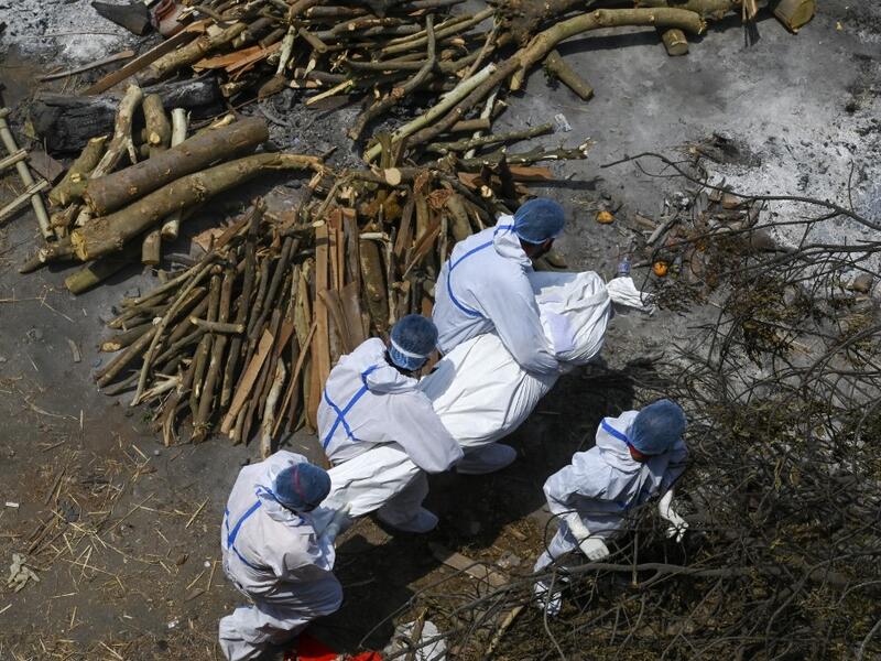 Family members and ambulance workers in PPE kit carry the body of a victim who died of the Covid-19 