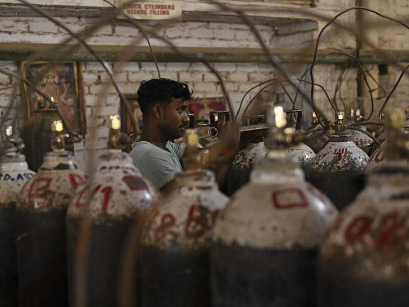 Workers are seen sorting oxygen cylinders that are being used for Covid-19 coronavirus patients 
