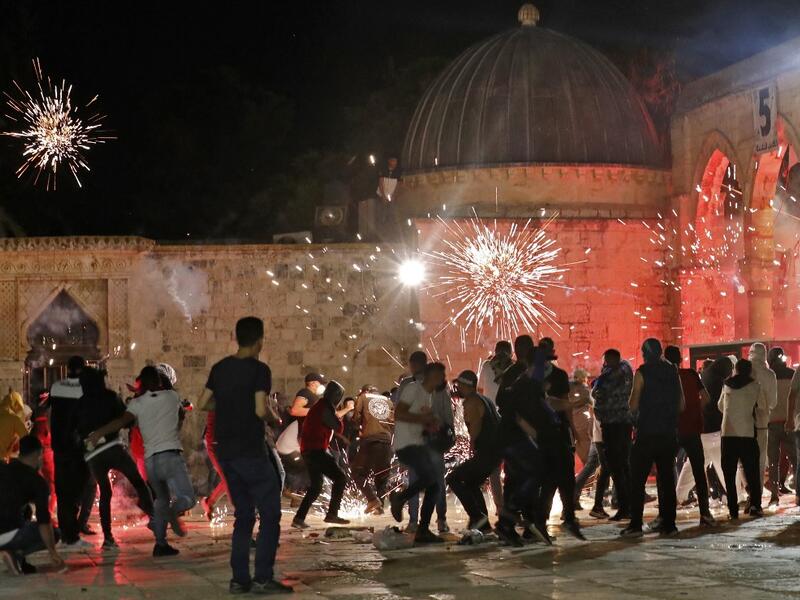 Stun grenades burst in the air amid clashes between Palestinian protesters and Israeli security forces at the al-Aqsa mosque compound in Jerusalem