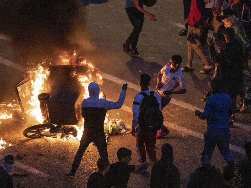 Migrants burn a skip during clashes with Moroccan riot police in the northern town of Fnideq, close to the border between Morocco and Spain's North African enclave of Ceuta on May 19, 2021. Migrants were still trying to cross from Morocco into the Spanish enclave of Ceuta on May 19, 2021, after a record 8,000 people poured over the border this week, escalating tensions between Rabat and Madrid. Some 5,600 migrants had already been sent back, Madrid said