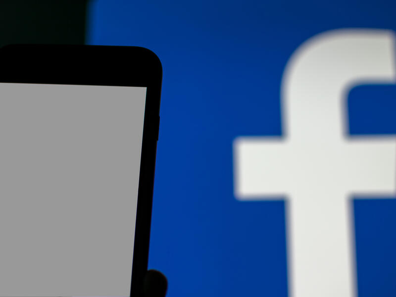 blank smartphone display and blurred Facebook logo