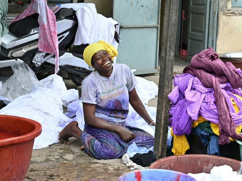 A dyer smiles as she poses for a photograph at Pathe'O house in the popular district of Treichville in Abidjan on March 31, 2021. A small self-taught tailor in his early years, the Ivorian-Burkinabe Pathe'O became the designer of African heads of state and celebrates the fiftieth anniversary of his brand, leading the "fight" for the recognition of fashion on the continent